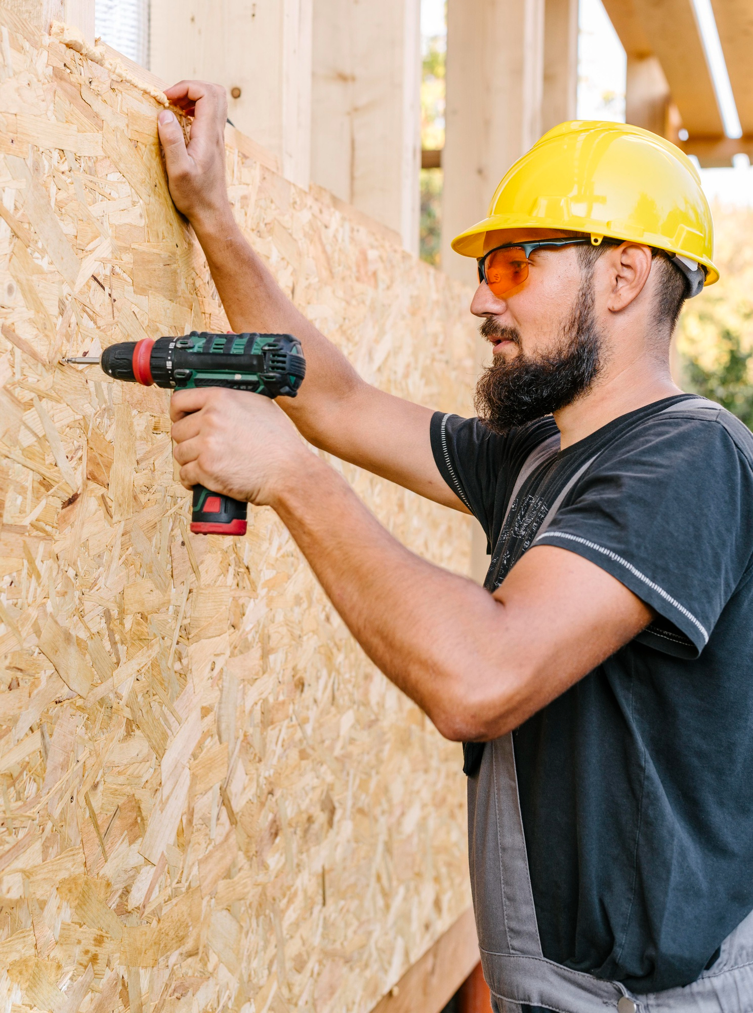 vista-lateral-trabajador-construccion-perforacion-madera-contrachapada